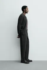 Pantalón de corte regular fit, color negro, confeccionado en tejido elástico. Presenta cintura elástica, cierre frontal con cremallera y botón, bolsillos laterales y bolsillos traseros de vivo.