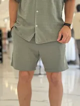 Bermuda de tejido texturizado color verde militar, con bolsillos laterales y cordón ajustable en la cintura.