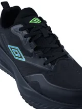 Championes deportivos Umbro modelo Fly, color negro con detalles en azul y verde neón en el logo lateral y la parte trasera. Presentan una suela robusta y diseño ergonómico.