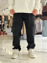 Pantalón cargo de jean negro de corte relajado, con bolsillos laterales con solapa y diseño utilitario.