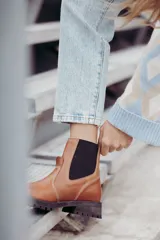 Bota tipo chelsea de cuero color marrón oscuro, con paneles laterales elásticos y suela track robusta con plataforma.