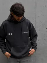 Canguro con capucha de color negro con efecto lavado, manga larga y bolsillo frontal tipo canguro. Presenta un pequeño estampado gráfico en el pecho con el logo de la marca.