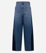 Pantalón de jean modelo wide leg con cintura media y cierre tradicional. Presenta un diseño bicolor con un recorte lateral en tono más oscuro que contrasta con el resto de la prenda, aportando una silueta alargada.