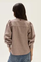 Camisa de manga larga con diseño de cuadros en tonos rosa y bordó. Presenta cuello mao, cierre frontal con botones y detalles de bordados florales en la parte superior del pecho. Las mangas son abullonadas con puños ajustados.