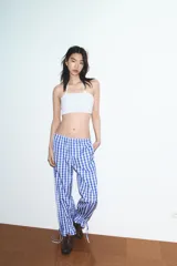 Pantalón de nylon con estampado de cuadros vichy azul y blanco. Presenta cintura elástica y bajo con volante fruncido y elástico.