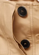 Chaleco oversize color beige, sin mangas, con cuello de solapa, cuatro bolsillos de parche con solapa en la parte delantera, fruncido elástico en la cintura y cierre frontal con botones.