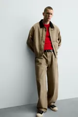 Cazadora de corte relajado confeccionada en algodón con efecto lavado. Presenta cuello de solapa en contraste de color negro, cierre frontal con cremallera oculta y alamares metálicos, bolsillos laterales de vivo y mangas largas.