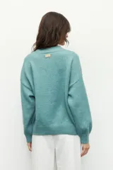 Polera negra de tejido de punto, con cuello redondo a la base y mangas largas abullonadas con puños elásticos.