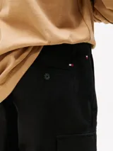 Pantalón corto tipo cargo de sarga de algodón elástico, color negro, con corte amplio y pierna recta. Presenta bolsillos ribeteados en la cintura, bolsillos laterales tipo cargo y un bolsillo trasero de ojal con botón.