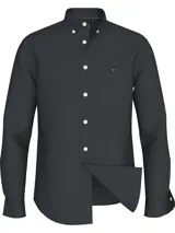 Camisa de popelina de algodón color negro, con cuello abotonado, mangas largas con puños abotonados y logo de Tommy Hilfiger bordado en el pecho. Confeccionada con tecnología Flex que proporciona elasticidad en cuatro direcciones.
