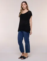 Blusa negra de tejido de punto fino con hilos de lúrex brillante, escote redondo amplio, mangas cortas con hombros caídos y silueta semi holgada.