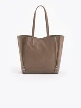 Cartera tipo shopper de cuero vacuno con textura graneada. Presenta un diseño amplio con cierres decorativos verticales en los laterales y manijas largas para llevar al hombro.