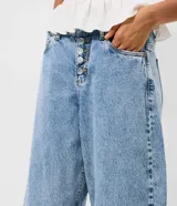 Pantalón baggy balloon de jean negro, con cintura media, cierre frontal con fila de botones y bolsillos funcionales.