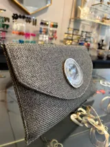 Sobre de mano de fiesta, color gris, con aplique de piedra ágata natural en el centro. Incluye asa de cadena metálica plateada para colgar al hombro.
