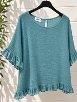 Blusa color verde turquesa con textura arrugada, escote redondo, mangas cortas amplias con volados y ruedo con volados. Cuenta con una pequeña abertura en la espalda con cierre de botón.