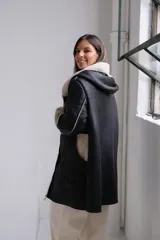 Tapado de cuero sintético negro con interior y detalles en corderito sintético color crema. Presenta capucha, cierre frontal y mangas largas con puños vueltos.