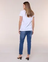 Remera de silueta recta confeccionada en algodón y elastano, de color blanco. Presenta escote redondo, mangas cortas, ruedo recto con tajos laterales y un diseño destacado en la pechera con aplique de piedras a tono.