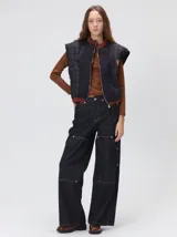 Chaleco de corte cuadrado con diseño bicolor en tonos terracota y crema. Presenta cierre frontal metalizado, parches de nylon en el pecho, interior forrado en corderito y cordón ajustable en el ruedo.