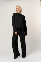 Sweater de punto negro con cuello alto tipo polera, mangas largas y corte relajado.