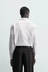 Camisa de corte slim fit confeccionada en tejido de algodón. Presenta cuello italiano, manga larga con puños abotonados y cierre frontal mediante botonadura clásica.