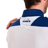 Chomba deportiva Diadora de corte clásico, con diseño bicolor en azul marino y blanco. Presenta cuello polo con cierre de botones y logo de la marca estampado en el pecho.