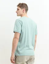 Remera tipo henley de manga corta, color beige, con cuello redondo y cartera de botones frontal.