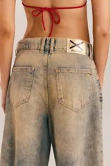 Bermuda de denim con efecto acid wash y lavado desgastado en tonos beige y celeste, de calce ancho y relajado, con largo a la rodilla y ruedo deshilachado.