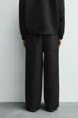Pantalón de corte wide fit confeccionado en tejido técnico con efecto neopreno. Presenta cintura elástica ajustable con cordón, perneras anchas con costura frontal, bolsillos laterales y bolsillos traseros de plastrón.