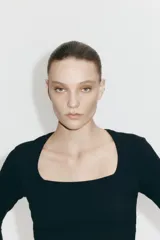 Remera negra de manga larga, entallada, con escote cuadrado pronunciado.