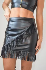 Minifalda negra de cuero sintético con flecos diagonales en el frente.