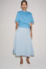 Falda midi de tiro alto en color negro, con diseño en línea evasé y cierre de cremallera oculta en la costura.