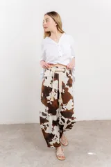 Pantalón ancho de lino con estampado de manchas de vaca en tonos marrón y blanco. Incluye cinturón de soga trenzada con flecos.