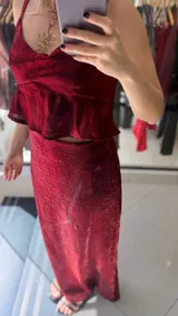Falda midi de corte recto, confeccionada en tela satinada con textura arrugada en color bordó. Presenta un diseño elegante y fluido.
