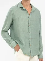 Camisa de manga larga confeccionada 100% en lino, color verde claro, con calce recto y relajado. Presenta frente abotonado con botones de coco con logo y el patch característico de Polonio.