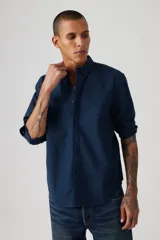 Camisa de manga larga azul marino, con cuello abotonado y logo bordado en el pecho.