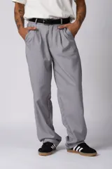 Pantalon sastrero de corte baggy, color gris, con pinzas delanteras y cierre de cremallera con botón. Presenta un diseño de silueta amplia y relajada con bolsillos laterales.