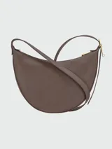 Cartera tipo bandolera de cuero granulado, con diseño de media luna y correa ajustable. Cuenta con cierre superior y herrajes metálicos discretos.