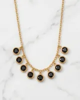 Collar de acero con baño de oro, compuesto por una cadena fina y ocho dijes circulares con circonias negras engastadas en un reborde dorado.