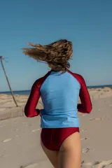 Traje de baño de dos piezas con remera de lycra celeste con mangas largas color borgoña y bombacha de lycra tiro alto color borgoña.