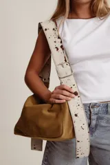 Bolso tipo hobo de cuero gamuzado color camel/marrón, con correa ancha ajustable estampada con efecto vaca/pelo con manchas marrones.