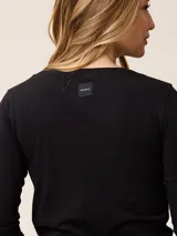 Remera de manga larga color gris, con cuello en V y logo bordado de un pájaro en el pecho.