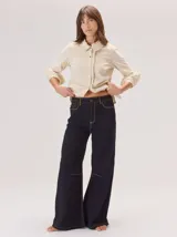 Pantalon de corte ancho y holgado, confeccionado en mezcla de algodón, viscosa y lino. Presenta costuras decorativas, pinzas debajo de la rodilla, bordado de monograma en el bolsillo delantero y pespuntes a contratono.