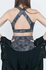 Top deportivo gris con estampado abstracto en negro, espalda cruzada y compresión alta.