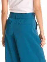 Pantalón de corte palazzo en color verde militar, con tiro alto, doble abotonadura frontal y pinzas. Presenta una silueta de pierna ancha, bolsillos laterales funcionales y cintura elástica en la parte posterior.