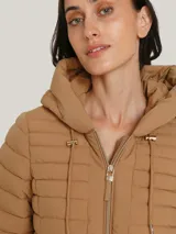Campera acolchada color camel con capucha ajustable con cordón, cierre frontal con cremallera y dos bolsillos delanteros con cierre.