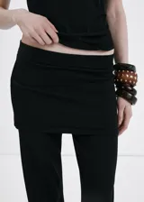 Pantalón de punto fino color negro, de diseño recto y tiro medio, con falda corta superpuesta integrada.