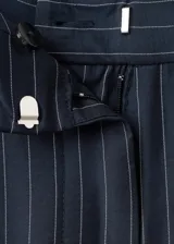 Pantalón azul marino de tiro alto con sutiles rayas diplomáticas blancas, de corte amplio y fluido con bolsillos laterales.