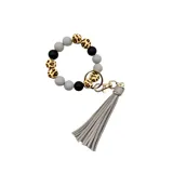 Llavero de muñeca con cuentas de silicona en color gris, negro y animal print. Incluye un fleco de cuero sintético color gris y un aro metálico dorado.