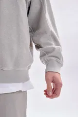 Sudadera gris claro con efecto lavado, de corte holgado y manga larga. Presenta una estampa minimalista en la espalda con el texto 'city pulse', 'street vibe' y 'subway beat'.