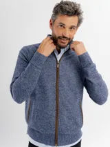 Campera tejida de punto jaspeado en tono azul, con cierre frontal completo, cuello alto y detalles de ribete en color marrón en los bolsillos y a lo largo del cierre. Presenta puños y ruedo acanalados.